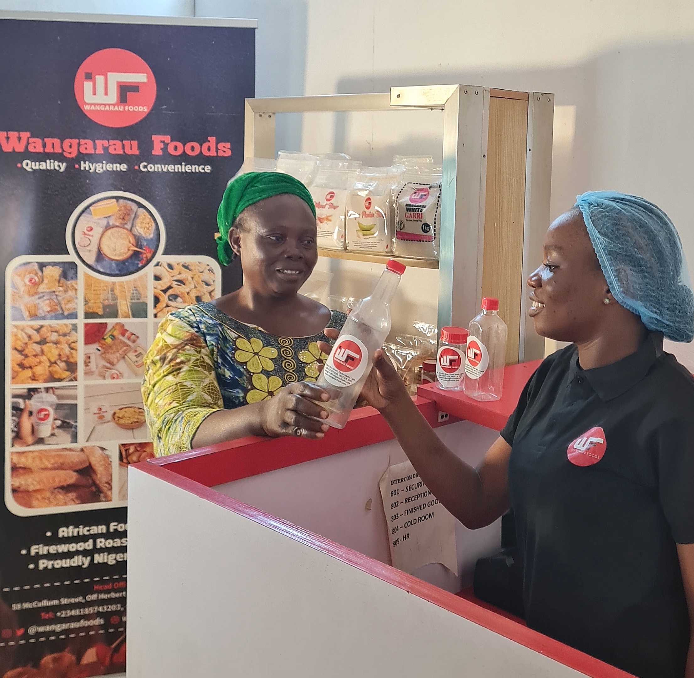Customer handing over a plastic bottle with Wangaraufoods label to a staff member at the store.
